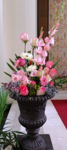 Altar arrangement of pink gladioli, gerbera daisies, Esperance roses, Pink Love roses, thistle, green hypericum, palmetto, heather and spray roses.