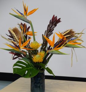 This large architectural arrangement is heavy with symbolism. Each bird of paradise represents a law of library science. The two dried banksia protea represent the action behind the screen and in front of the screen.